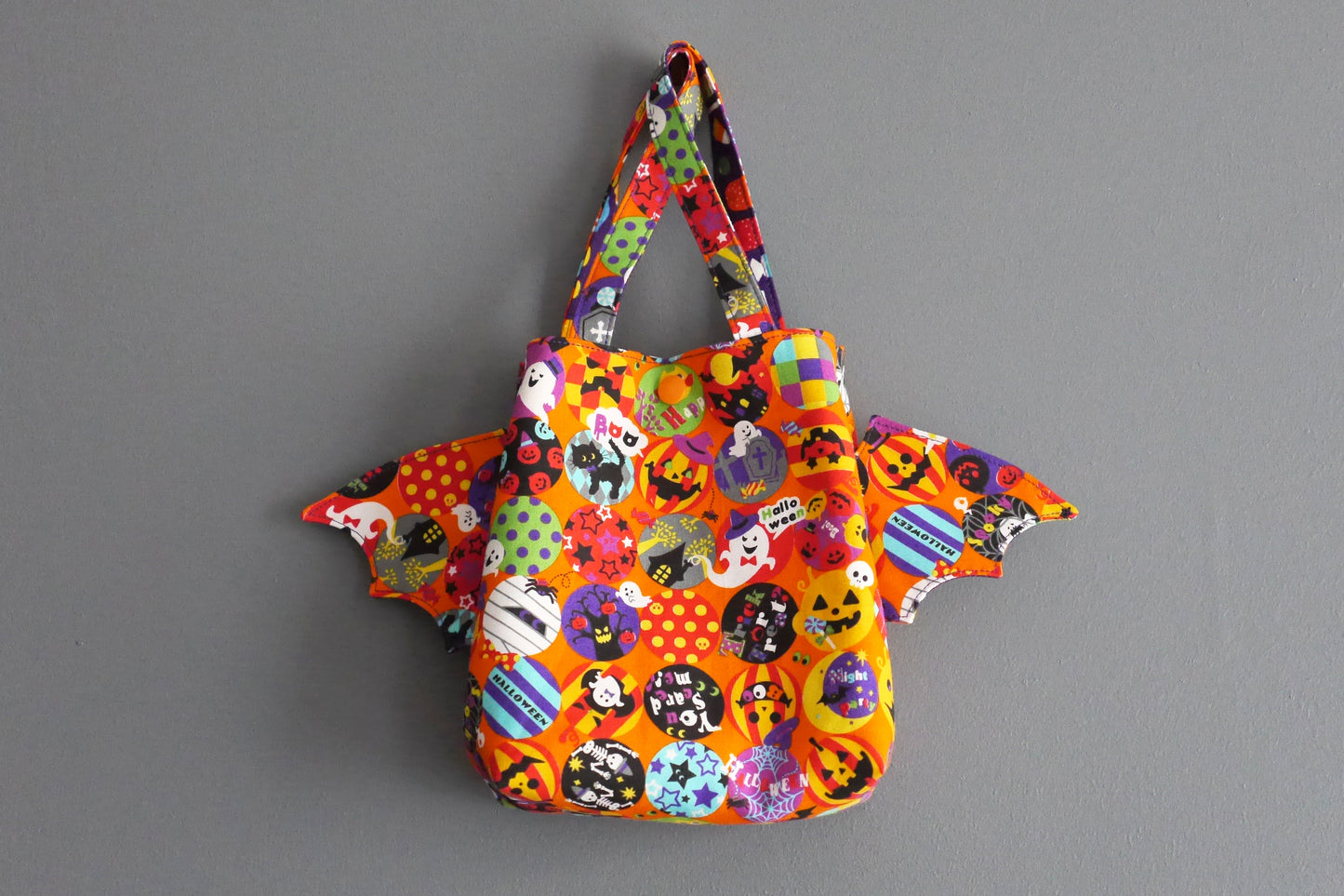 Sac à bonbons halloween panier enfant ailes de chauve-souris tissu orange coloré violet friandises monstres fantômes porté poignet