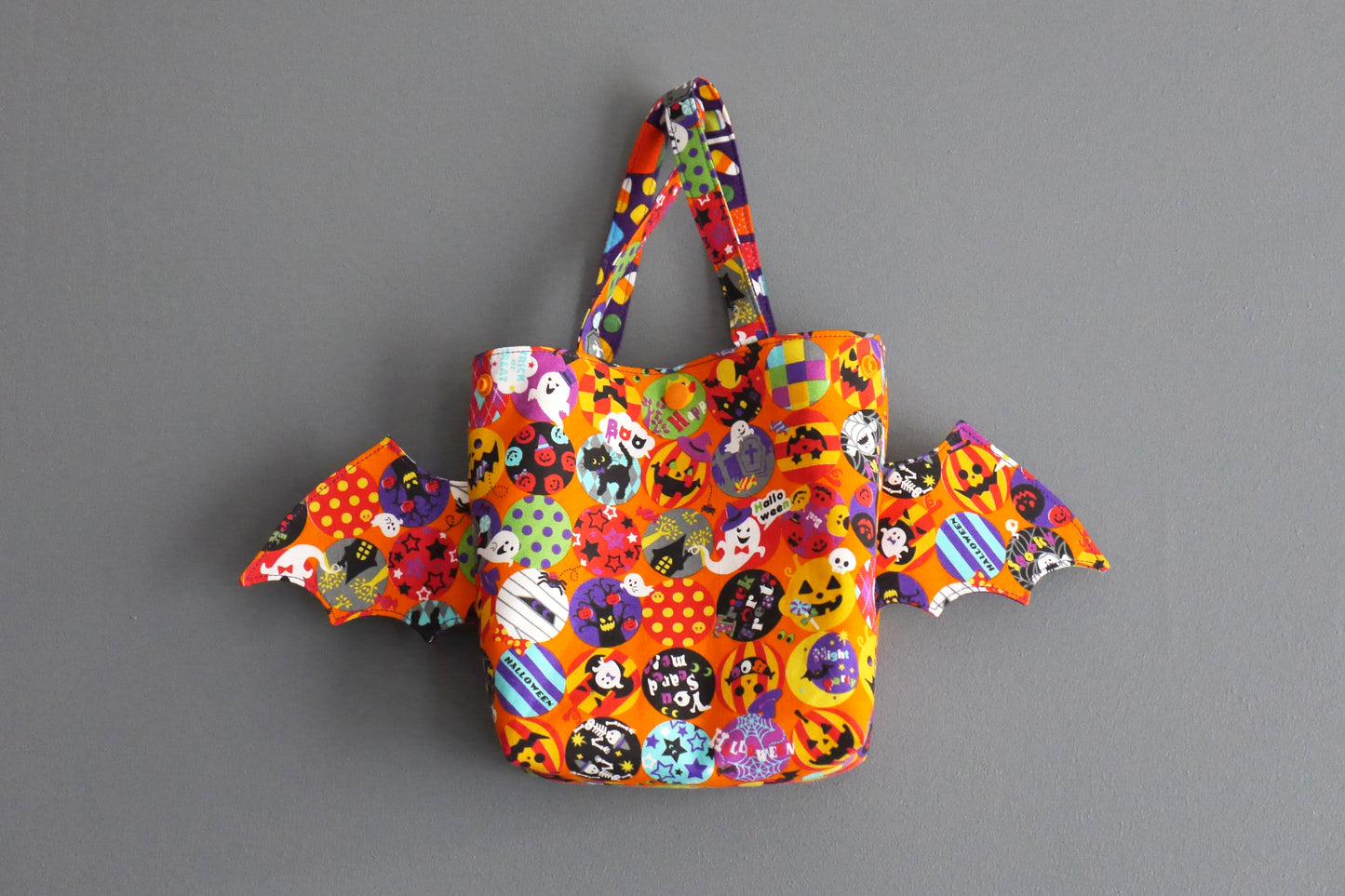 Sac à bonbons halloween panier enfant ailes de chauve-souris tissu orange coloré violet friandises monstres fantômes porté poignet
